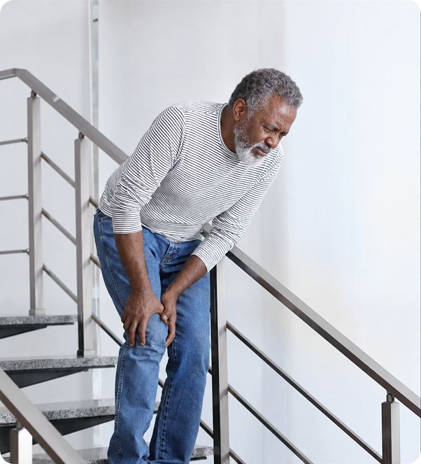 Older man holding his knee in pain on a staircase