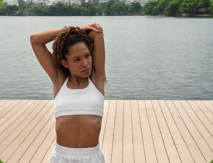 Woman stretching her arms overhead on a lakeside deck