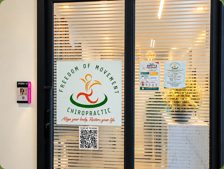 Glass office door with the Freedom of Movement Chiropractic logo and a booking QR code