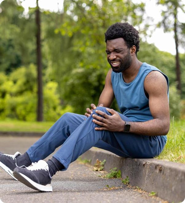 Man sitting on a curb holding a painful knee