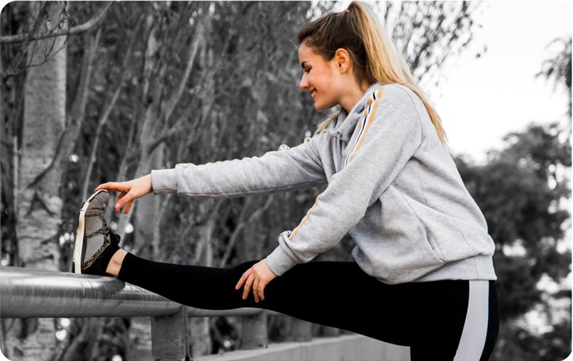 Woman stretching her leg on a railing outdoors